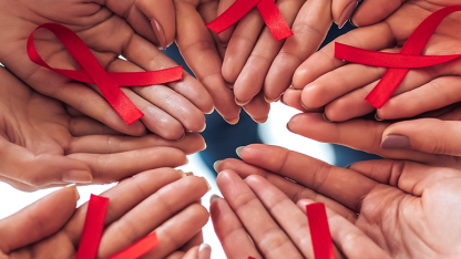 Mehrere Hände halten gemeinsam rote Solidaritätsschleifen