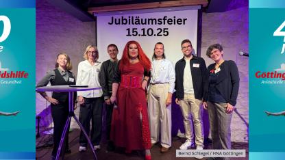 Das Bild zeigt das Team der Göttinger Aidshilfe - Vorstand & Haupamtliche - zusammen mit der Moderatorin & Drag-Queen Renelopé Fauxwell