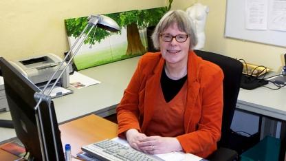 Person im roten Kostüm sitzt am Schreibtisch