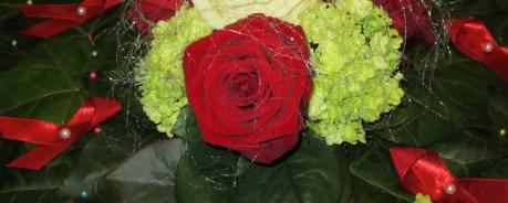 Gesteck mit Rosen und Roten Schleifen zur Erinnerung an Menschen, die an HIV/Aids verstorben sind