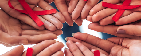 Mehrere Hände halten gemeinsam rote Solidaritätsschleifen