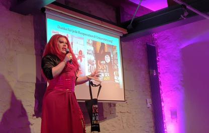 Renelopé Fauxwell zeigt die Safer-Sex-Stoffbeutet der Göttinger Aidshilfe auf der Bühne der Jubiläumsfeier